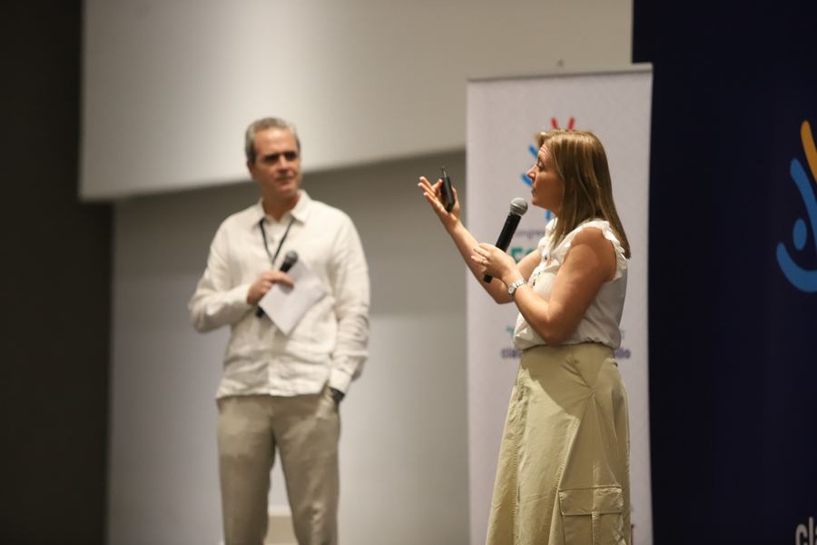 Dany y otro ponente, cada uno con micrófono, dialogan de pie frente al público.
